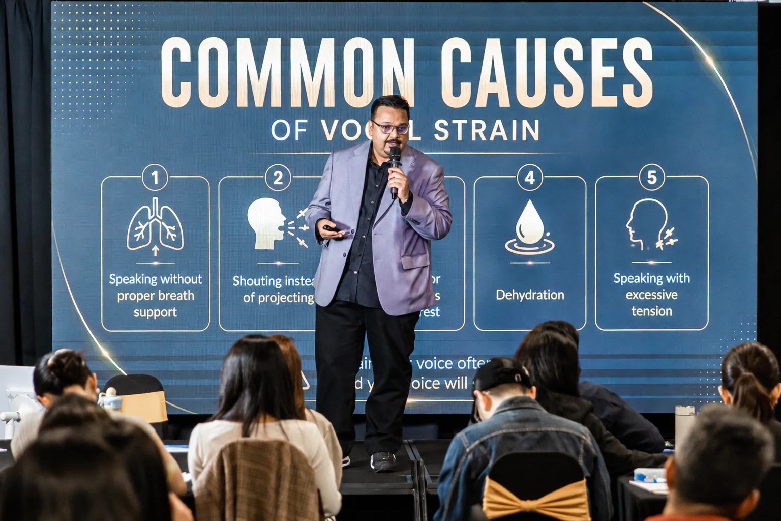 Navin Nair presenting a lesson on vocal strain to a seated audience